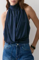 Blusa de tela liviana con acabado satinado, color azul marino, con diseño de escote halter fruncido y espalda descubierta.