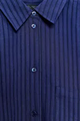Camisa de corte oversize confeccionada en mezcla de viscosa con textura de rayas verticales en jacquard. Presenta cuello solapa, cierre frontal con botones, bolsillo de plastrón en el pecho, mangas largas con puños anchos y bajo redondeado.