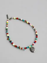 Collar de cuentas de cristal multicolor de diversas formas y tamaños, con un dije central de metal plateado con relieve de escudo.