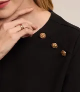 Blusa negra de crepé con cuello redondo, mangas cortas y botones dorados decorativos en los hombros.
