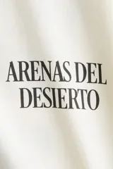 Remera oversized de punto suave de algodón, color blanco, con cuello redondo acanalado, hombros caídos y diseño estampado en el frente con la frase 'Arenas del Desierto'.