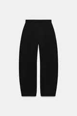 Pantalón balloon de tiro alto color negro, con diseño de pierna ancha, trabillas en la cintura, pespuntes marcados a tono y cierre frontal con cremallera, botón y ganchos metálicos.