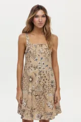 Vestido corto camel de lino y viscosa, con escote cuadrado, breteles anchos y diseño con godets. Presenta un estampado artesanal en tonos marrones y blancos.