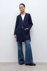 Sacón azul marino de corte largo, con cuello solapa, cierre frontal de dos botones dorados y bolsillos de parche.