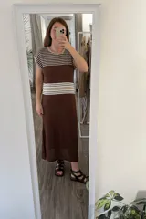 Vestido largo tejido color marrón con rayas horizontales beige y blancas en la parte superior, detalle calado en la parte inferior y tajos a los costados.