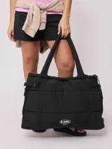 Bolso tipo tote bag de diseño acolchado en color negro, con correas ajustables y cierre lateral. Presenta el logo de la marca Rusty en la parte frontal.