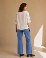 Blusa de lino color beige, de corte recto y holgado, con mangas tres cuartos con presilla y botón para arremangar.