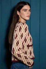 Saco de punto con diseño de rombos en tonos verde, amarillo y gris. Presenta cuello redondo, cierre frontal con botones y dos bolsillos delanteros con terminaciones en contraste.
