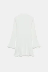 Vestido corto de punto rib color blanco, con cuello subido, manga larga y acabados ondulados en los puños y el bajo.