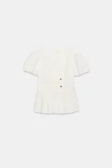 Top de color blanco con escote en pico, mangas cortas abullonadas y bajo con diseño peplum. Presenta detalle de botones dorados en la parte frontal y cierre lateral con cremallera oculta.