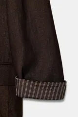 Blazer de lino color verde militar, con cuello solapa, hombreras y manga larga con puño revuelto con detalle a rayas. Cuenta con cierre frontal de un botón y bolsillos delanteros con solapa.