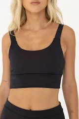 Top deportivo negro con tirantes anchos y largo intermedio. Cuenta con compresión media y espacio para agregar tazas.