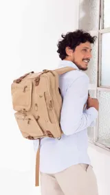 Mochila porta notebook de tela canvas color beige con detalles en cuero marrón. Tiene múltiples bolsillos con cierre y correas ajustables.