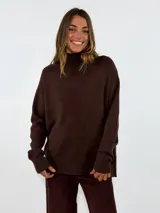 Sweater de punto color marrón, con cuello alto, manga larga y diseño holgado con puños y ruedo acanalados.
