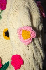 Sweater holgado de lana merino color marfil, con mangas con diseño de ochos y apliques bordados de flores en 3D de diversos colores.