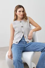 Chaleco tejido gris con botones de madera, sin mangas y cuello redondo.