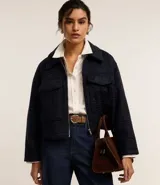 Campera corta azul marino de tejido boucle con cuello inglés, cierre frontal con cremallera y bolsillos grandes con solapa en el pecho.