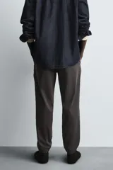 Pantalón tipo jogger de corte slim fit, confeccionado en tejido de algodón con elasticidad. Presenta cintura elástica ajustable con cordón, bolsillos frontales, bolsillos traseros de vivo y bajos con puños elásticos.