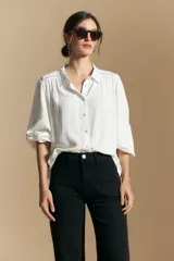 Camisa de manga larga color celeste, con cuello clásico, cierre frontal con botones y puños elastizados con volados. Presenta un diseño fluido con detalle de vainilla en la espalda.