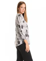 Buzo de tejido soft estampado, con cuello a la base y mangas largas con terminación fruncida. Presenta un diseño floral en tonos oscuros sobre base gris.