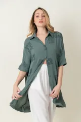 Camisa larga de manga corta, calce holgado, color verde con estampado de motivos en forma de medallones o cuadrados con diseño ornamental.