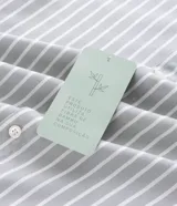 Camisa de corte regular confeccionada en una mezcla de bambú y poliéster, con diseño de rayas verticales en tono verde claro y blanco. Presenta cuello inglés, cierre frontal con botones y mangas largas con puños ajustables.
