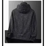 Campera cortaviento impermeable de la marca Uniteduy, color negro con estampado sutil de hojas. Cuenta con capucha, cierre frontal, tres bolsillos externos y uno interno. Es una prenda ultra liviana y transpirable, ideal para actividades al aire libre.