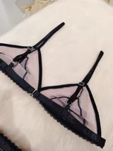 Conjunto de lencería compuesto por un corpiño triangular y una tanga regulable. Está confeccionado en microtul color tostado con detalles de encaje negro en los bordes y en las copas. El corpiño cuenta con breteles finos y la tanga presenta elásticos laterales ajustables.