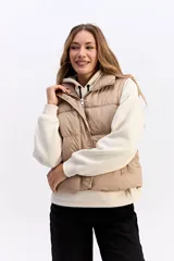 Chaleco matelaseado de color negro, con cuello alto, cierre frontal con broches y diseño acolchado con volumen.