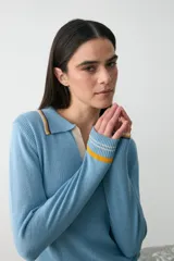 Remera de punto color celeste con cuello polo, manga larga y detalles de rayas en contraste en cuello, puños y ruedo.