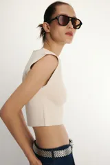 Top corto de punto color beige claro, con cuello redondo y mangas cortas tipo hombrera.