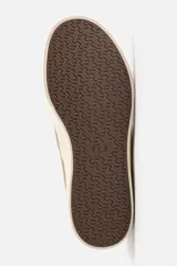 Zapatilla tipo slip-on de lona color taupe, con elástico lateral para facilitar el calce y suela de goma gruesa color crema.