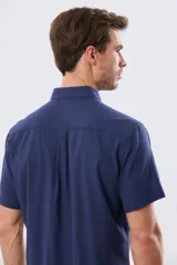 Camisa de manga corta confeccionada en mezcla de lino y algodón, color beige, con cuello camisero abotonado, bolsillo frontal en el pecho y cierre de botones.