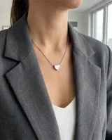 Collar de acero con cadena fina y dije pasante en forma de corazón con incrustación de nácar.