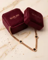 Collar de cadena de eslabones en acero con baño de oro rosa, que presenta tres dijes circulares con centro de ónix negro y bordes grabados con números romanos.
