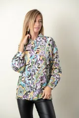 Camisa de satén estampada con motivos geométricos en tonos lila, celeste, verde y amarillo. Tiene cuello clásico, mangas largas con puños abotonados y cierre frontal con botones.