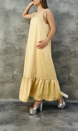 Vestido largo color beige, de breteles finos con lazo y falda con volados.