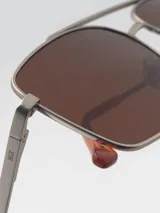 Lentes de sol con montura metálica negra, forma cuadrada y lentes verdes.