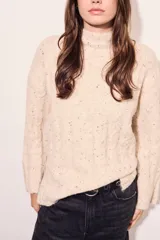 Sweater color crema con cuello alto, tejido de punto con textura y mangas largas con puños acampanados.