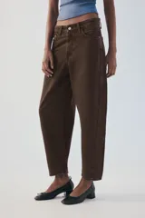 Jeans de tiro medio color marrón con diseño de volumen crop, silueta holgada en las piernas y cinco bolsillos tradicionales. Cierre frontal con cremallera y botón metálico.