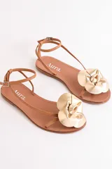 Sandalias bajas color cuero con tiras finas y aplique de flor dorada.