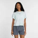 Remera deportiva New Balance de corte relajado y mangas cortas, confeccionada en tejido ligero con tecnología de absorción de humedad. Presenta aberturas laterales y logo reflectante en el pecho.