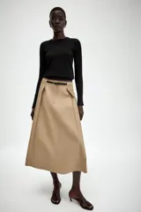 Falda midi de tiro alto en color beige, con diseño evasé y pliegues laterales. Incluye un cinturón fino a contraste en color negro con hebilla metálica y cierre frontal con cremallera y gancho.
