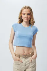 Top corto de manga corta, color negro con efecto desgastado o acid wash, cuello redondo y costuras verticales que definen la silueta.