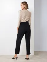 Enterito combinado de fiesta marca Julia Jordan. El torso es de lentejuelas color beige con escote en V cruzado y mangas largas abullonadas. La cintura es elastizada con lazo de ajuste y el pantalón es negro con bolsillos verticales. La espalda tiene cierre invisible y el torso está forrado.