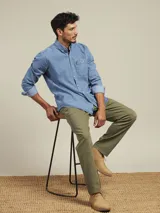 Pantalón de vestir color beige, de corte recto, con bolsillos laterales y traseros. Se ajusta a la cintura con cinturón de cuero marrón.