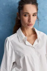 Camisa blanca de algodón, de calce relajado, con cuello camisero, frente abotonado y mangas largas abullonadas.