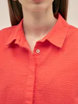 Camisa de manga corta con cuello camisero y botones anacarados, confeccionada en tejido seersucker con estampa floral.