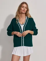 Cárdigan de punto verde oscuro con cuello en V y botones. Presenta ribetes blancos en el cuello, el frente y los puños.