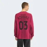 Suéter de punto Adidas en color bordó, inspirado en el estilo de las camisetas de fútbol retro. Presenta cuello redondo, mangas largas con las tres tiras características de la marca en blanco y detalles perforados en la trama. Incluye el logo del Trifolio y un escudo circular bordados en el pecho, junto con el texto "adidas" en contraste.